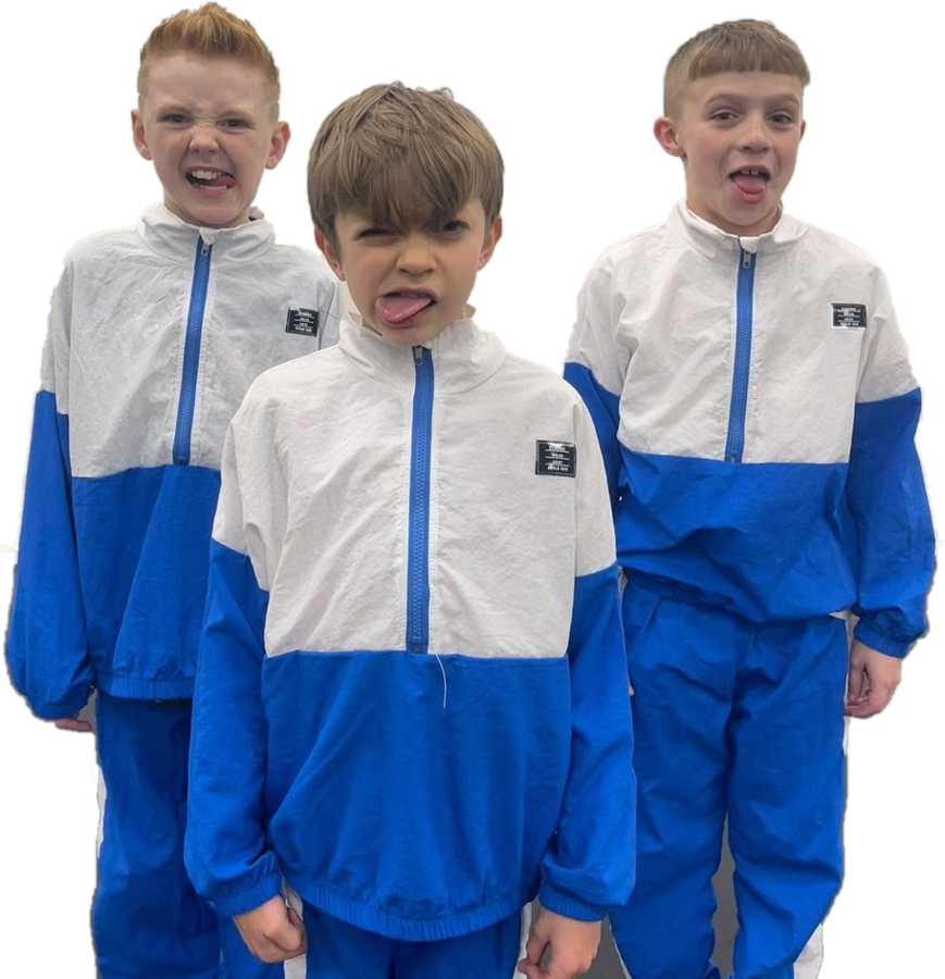 Three Tycoons boys in matching blue and white tracksuits pulling funny faces